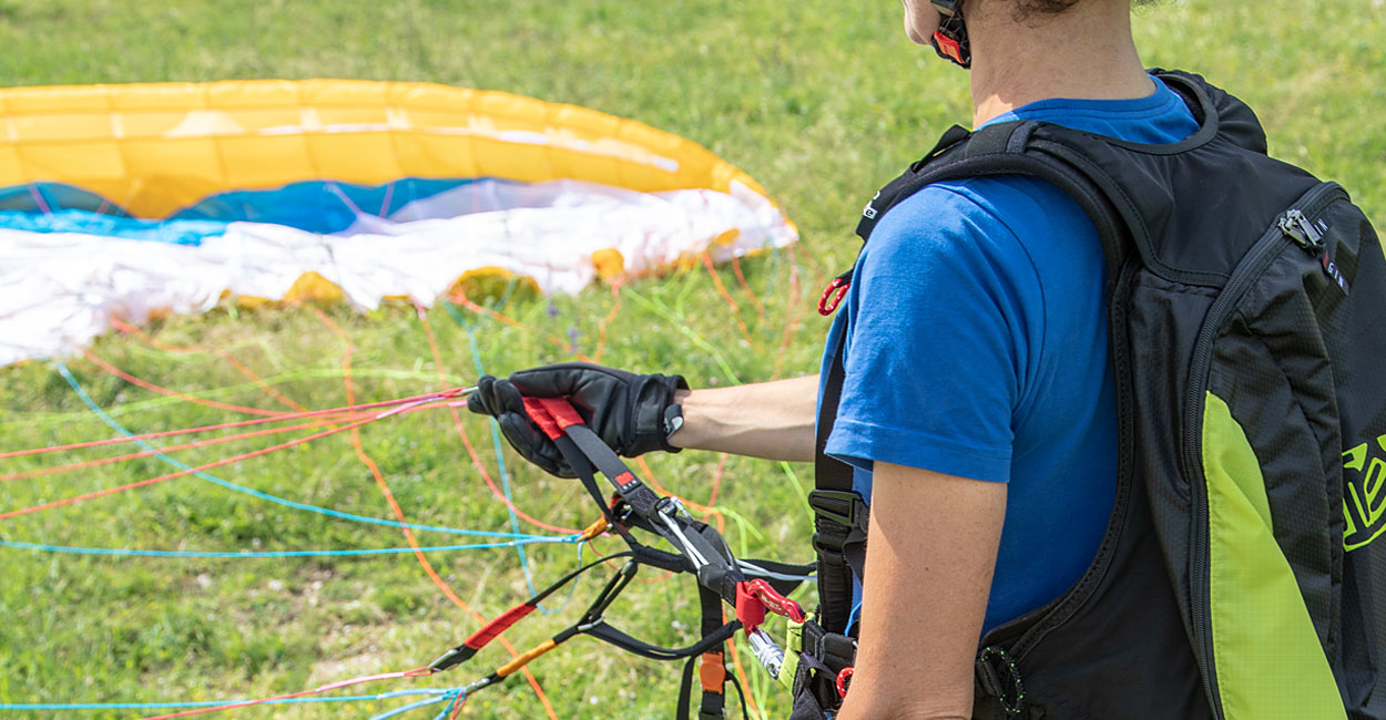 Pilot paralotni od tyłu, trzymający za taśmy nośne, a przed nim rozłożone skrzydło